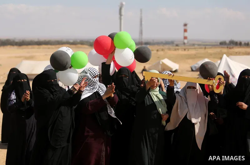 Palestinian women hold balloons during a protest demanding the right to return to their homeland, at the Israel-Gaza border, in Rafah in the southern Gaza Strip on April 10, 2018. Photo by Ashraf Amra