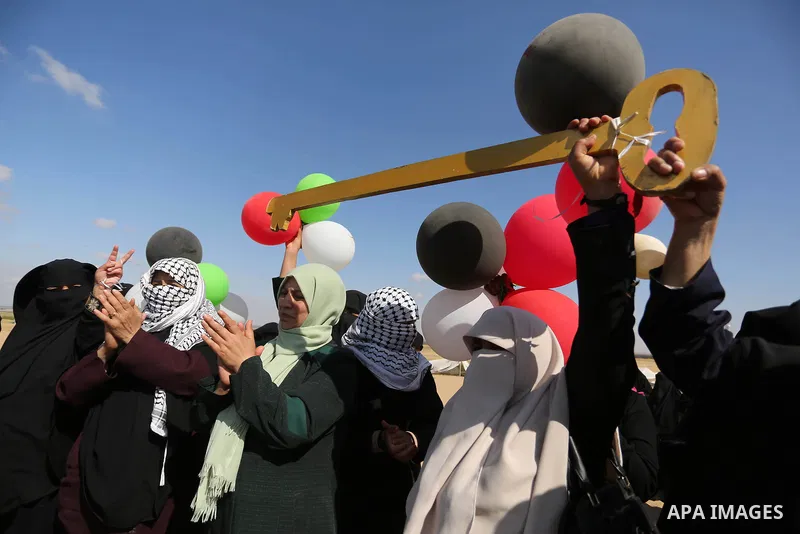Palestinian women hold balloons during a protest demanding the right to return to their homeland, at the Israel-Gaza border, in Rafah in the southern Gaza Strip on April 10, 2018. Photo by Ashraf Amra