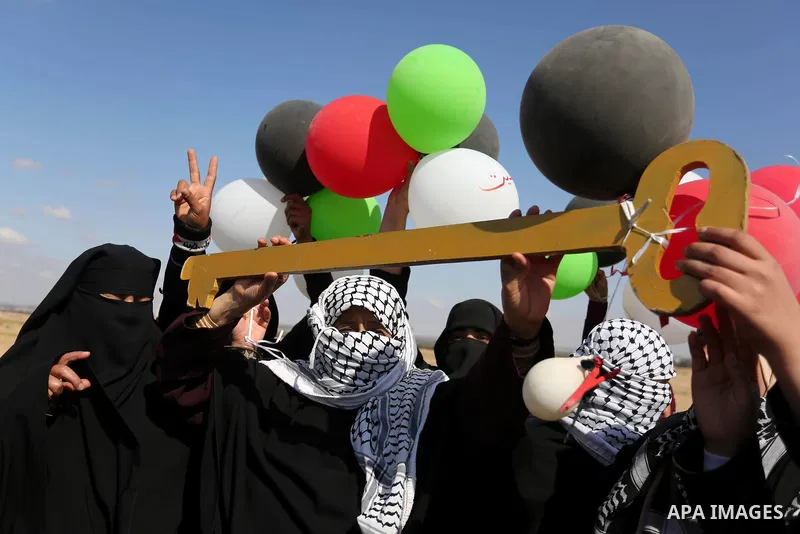 Palestinian women hold balloons during a protest demanding the right to return to their homeland, at the Israel-Gaza border, in Rafah in the southern Gaza Strip on April 10, 2018. Photo by Ashraf Amra