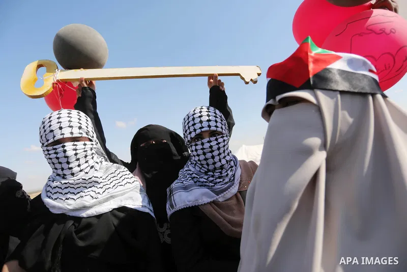 Palestinian women hold balloons during a protest demanding the right to return to their homeland, at the Israel-Gaza border, in Rafah in the southern Gaza Strip on April 10, 2018. Photo by Ashraf Amra