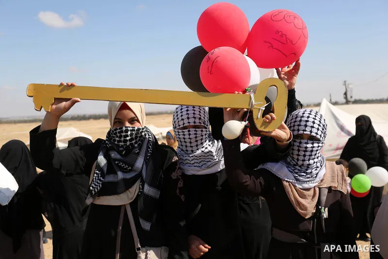 Palestinian women hold balloons during a protest demanding the right to return to their homeland, at the Israel-Gaza border, in Rafah in the southern Gaza Strip on April 10, 2018. Photo by Ashraf Amra