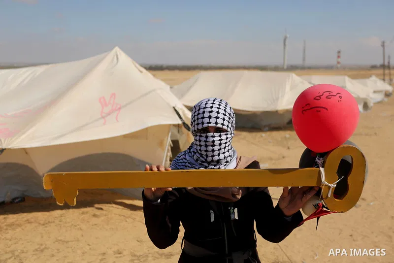 A Palestinian woman holds symbolic key and balloons during a protest demanding the right to return to their homeland, at the Israel-Gaza border, in Rafah in the southern Gaza Strip on April 10, 2018. Photo by Ashraf Amra