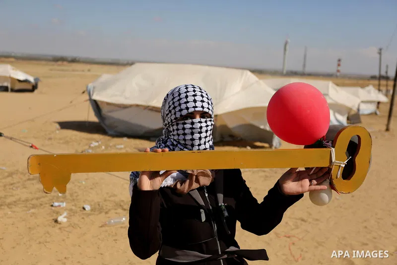 A Palestinian woman holds symbolic key and balloons during a protest demanding the right to return to their homeland, at the Israel-Gaza border, in Rafah in the southern Gaza Strip on April 10, 2018. Photo by Ashraf Amra