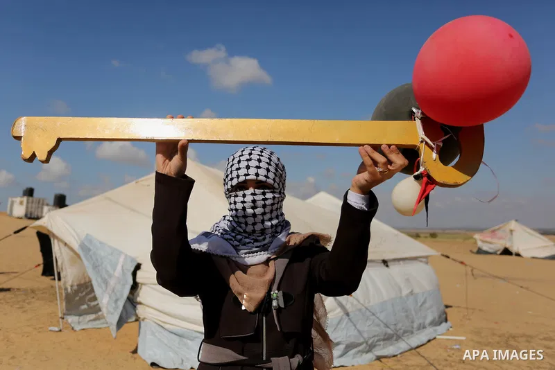 A Palestinian woman holds symbolic key and balloons during a protest demanding the right to return to their homeland, at the Israel-Gaza border, in Rafah in the southern Gaza Strip on April 10, 2018. Photo by Ashraf Amra