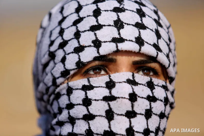 A Palestinian woman looks on during a protest demanding the right to return to their homeland, at the Israel-Gaza border, in Rafah in the southern Gaza Strip on April 10, 2018. Photo by Ashraf Amra