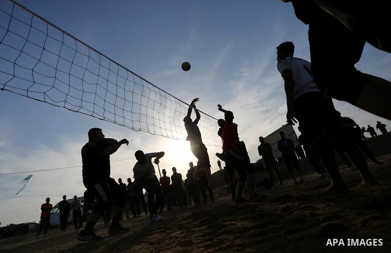 Palestinians play volleyball near tents during a tent city protest demanding the right to return to their homeland, at the Israel-Gaza border in the east of Gaza city on April 11, 2018. Photo by Ashraf Amra