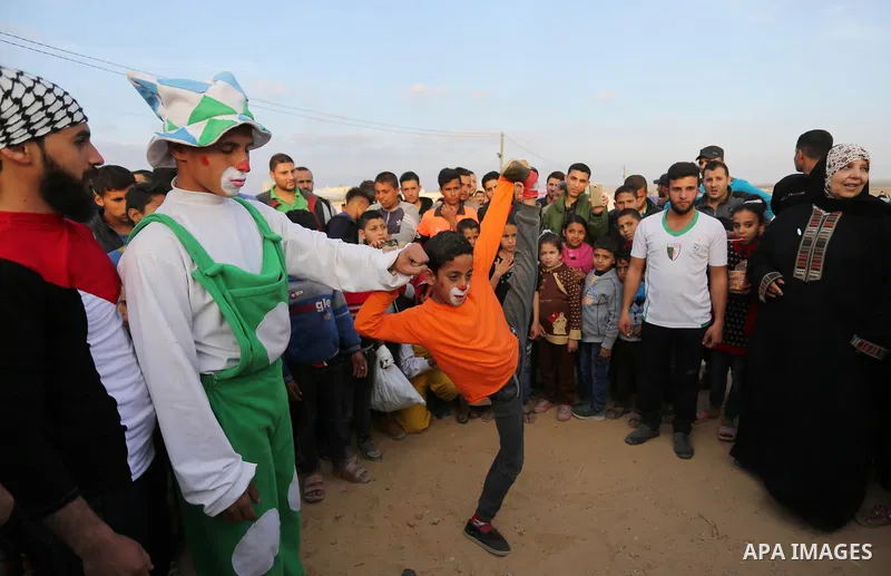 A Palestinian clown show his skills near tents during a tent city protest demanding the right to return to their homeland, at the Israel-Gaza border in the east of Gaza city on April 11, 2018. Photo by Ashraf Amra