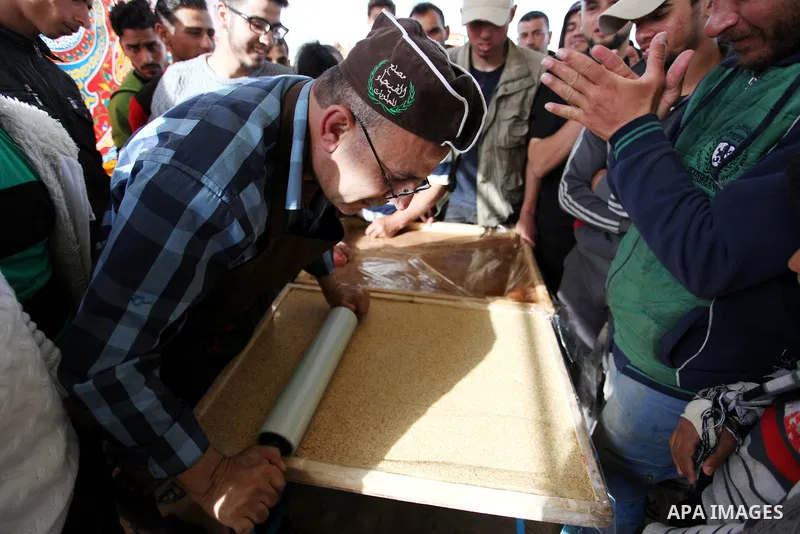 A Palestinian man prepares a traditional sweet known as "Sesame" during a tent city protest demanding the right to return to their homeland, at the Israel-Gaza border in the east of Gaza city on April 12, 2018. Photo by...