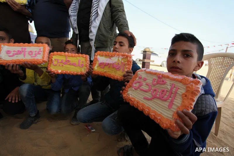 Palestinians show traditional sweets which was prepared during a tent city protest demanding the right to return to their homeland, at the Israel-Gaza border in the east of Gaza city on April 12, 2018. Photo by Mahmoud A...