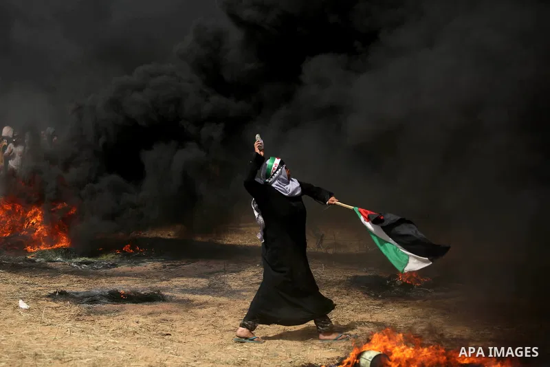 A Palestinian woman hurls stones towards Israeli security forces during clashes in a tent city protest where Palestinians demand the right to return to their homeland, at the Israel-Gaza border, in Khan Younis in the sou...