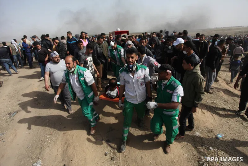 Members of Palestinian medical staff carry An injured Palestinian protester who was wounded during clashes with Israeli security forces in a tent city protest where Palestinians demand the right to return to their homela...