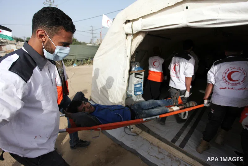 Members of Palestinian medical staff carry An injured Palestinian protester who was wounded during clashes with Israeli security forces in a tent city protest where Palestinians demand the right to return to their homela...