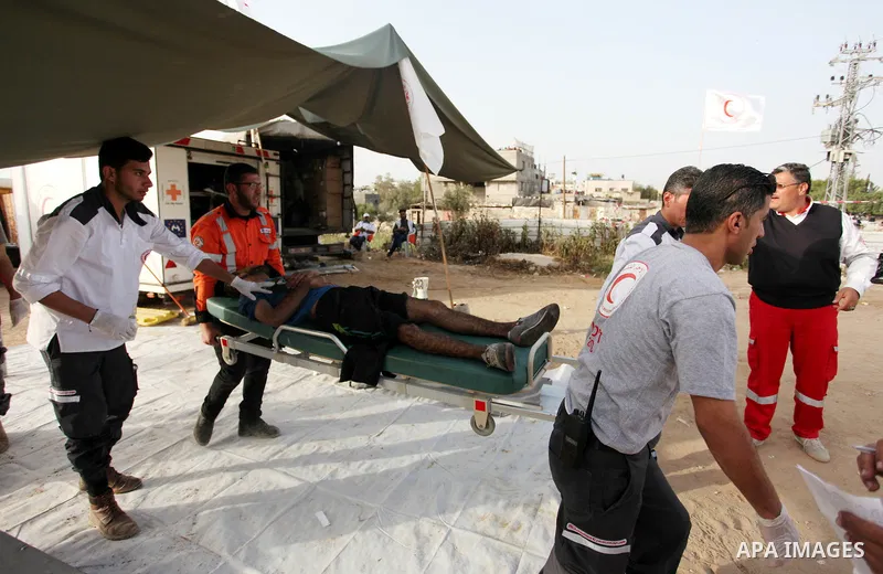 Members of Palestinian medical staff carry An injured Palestinian protester who was wounded during clashes with Israeli security forces in a tent city protest where Palestinians demand the right to return to their homela...