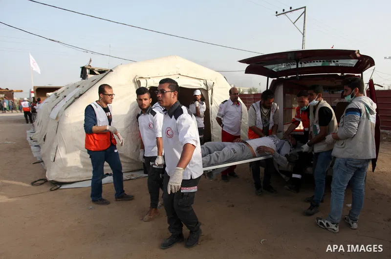 Members of Palestinian medical staff carry An injured Palestinian protester who was wounded during clashes with Israeli security forces in a tent city protest where Palestinians demand the right to return to their homela...