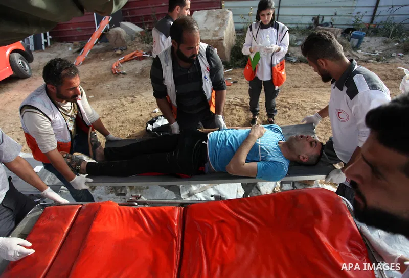 Members of Palestinian medical staff carry An injured Palestinian protester who was wounded during clashes with Israeli security forces in a tent city protest where Palestinians demand the right to return to their homela...