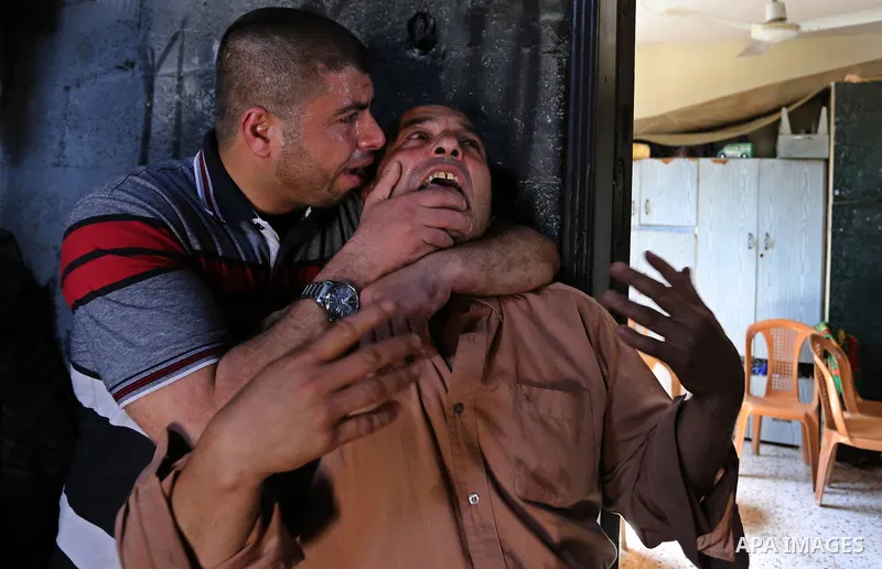 Palestinian men mourn during the funeral of of Islam Herzallah, 28, who was killed during clashes with Israeli security forces at the Israel-Gaza border, in Gaza City on April 14, 2018. Photo by Ashraf Amra