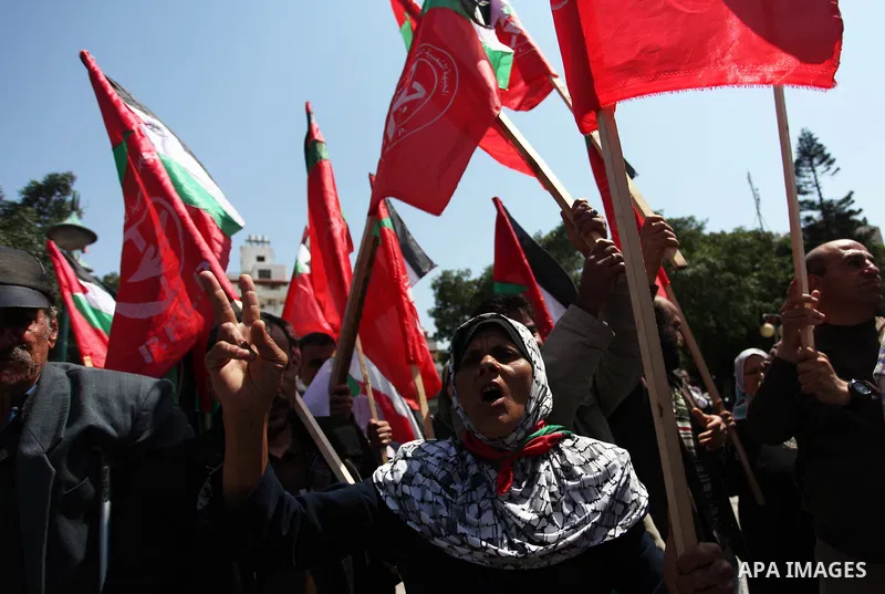 Palestinian protesters wave the flags during a protest against U.S. air strikes in Damascus, in Gaza city April 15, 2018. Photo by Mahmoud Ajour