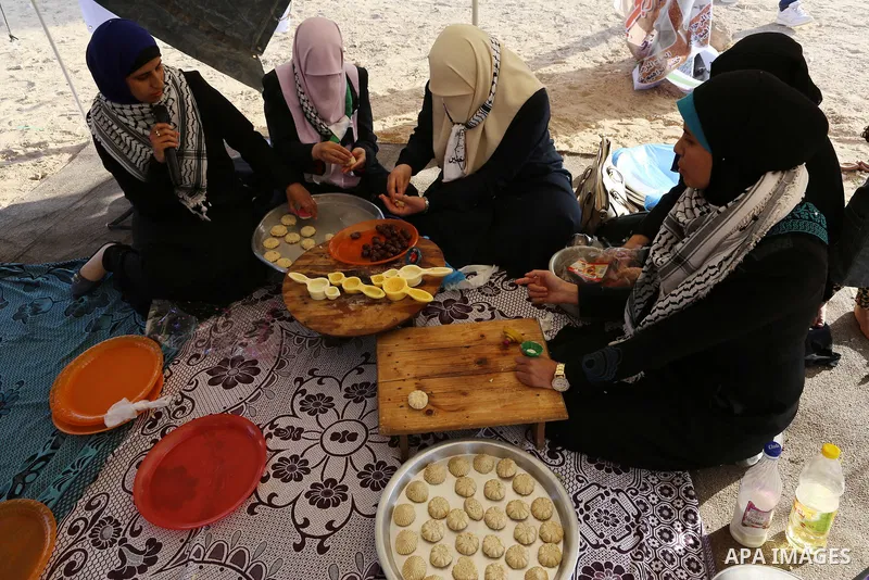 Palestinian women prepare traditional date-filled mini cakes during a tent city protest along Israel border with Gaza, demanding to return to their home land, east of Gaza City, April 16, 2018. Photo by Yasser Qudih