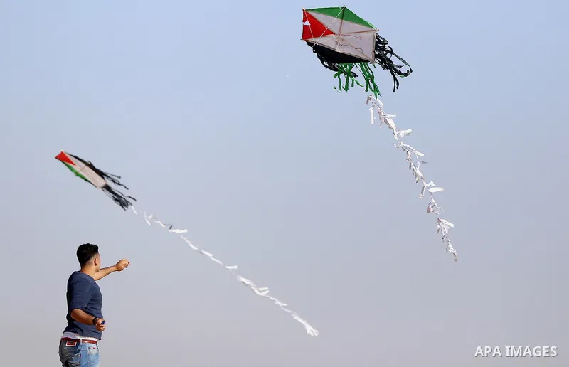 A Palestinian youth flies a kite during a tent city protest along Israel border with Gaza, demanding to return to their home land, east of Gaza City, April 16, 2018. Photo by Yasser Qudih