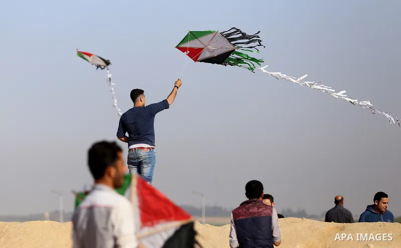 A Palestinian youth flies a kite during a tent city protest along Israel border with Gaza, demanding to return to their home land, east of Gaza City, April 16, 2018. Photo by Yasser Qudih