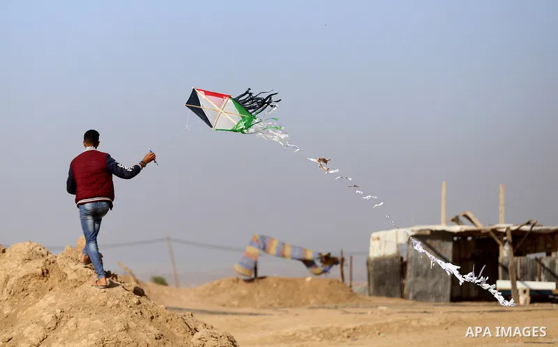 A Palestinian youth flies a kite during a tent city protest along Israel border with Gaza, demanding to return to their home land, east of Gaza City, April 16, 2018. Photo by Yasser Qudih