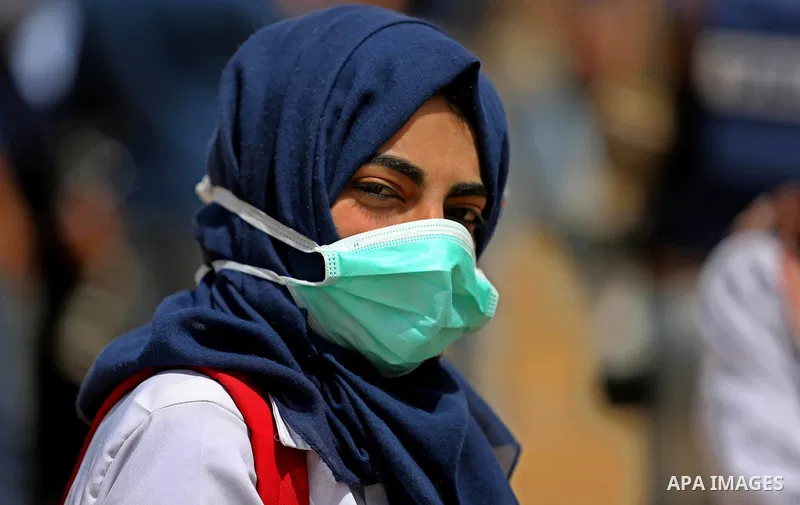 A picture taken on April 13, 2018, shows a Palestinian woman covers her face to protect herself from tear gas during clashes with Israeli security forces following a protest, on the Gaza-Israel border, in Khan Younis in...
