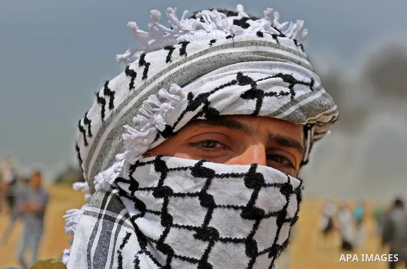 A picture taken on April 13, 2018, shows a Palestinian protester covers his face to protect himself from tear gas during clashes with Israeli security forces following a protest, on the Gaza-Israel border, in Khan Younis...