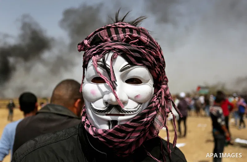A picture taken on April 13, 2018, shows a Palestinian protester covers his face to protect himself from tear gas during clashes with Israeli security forces following a protest, on the Gaza-Israel border, in Khan Younis...