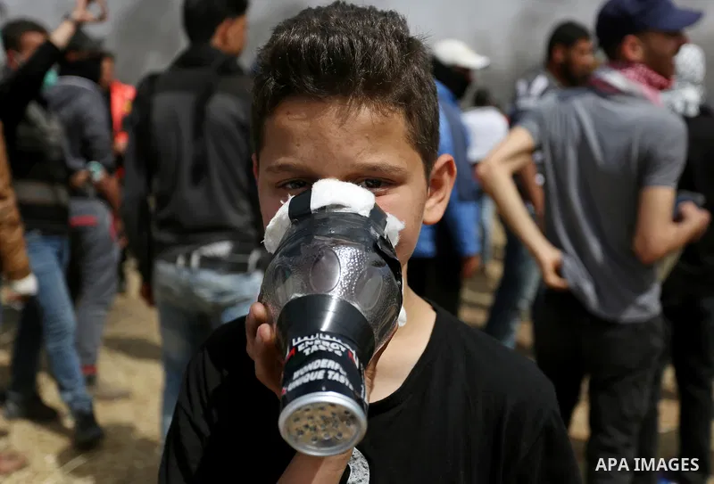 A picture taken on April 13, 2018, shows a Palestinian protester covers his face to protect himself from tear gas during clashes with Israeli security forces following a protest, on the Gaza-Israel border, in Khan Younis...