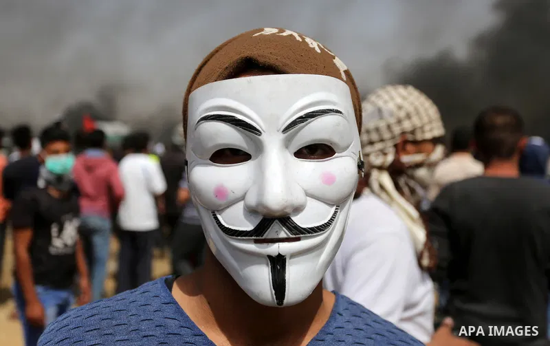A picture taken on April 13, 2018, shows a Palestinian protester covers his face to protect himself from tear gas during clashes with Israeli security forces following a protest, on the Gaza-Israel border, in Khan Younis...