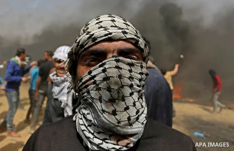 A picture taken on April 13, 2018, shows a Palestinian protester covers his face to protect himself from tear gas during clashes with Israeli security forces following a protest, on the Gaza-Israel border, in Khan Younis...