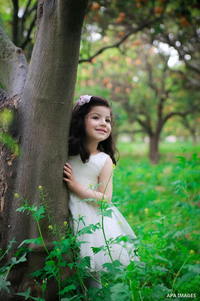 A pretty girl collects oranges at a field. Photo by Mahmoud Khattab