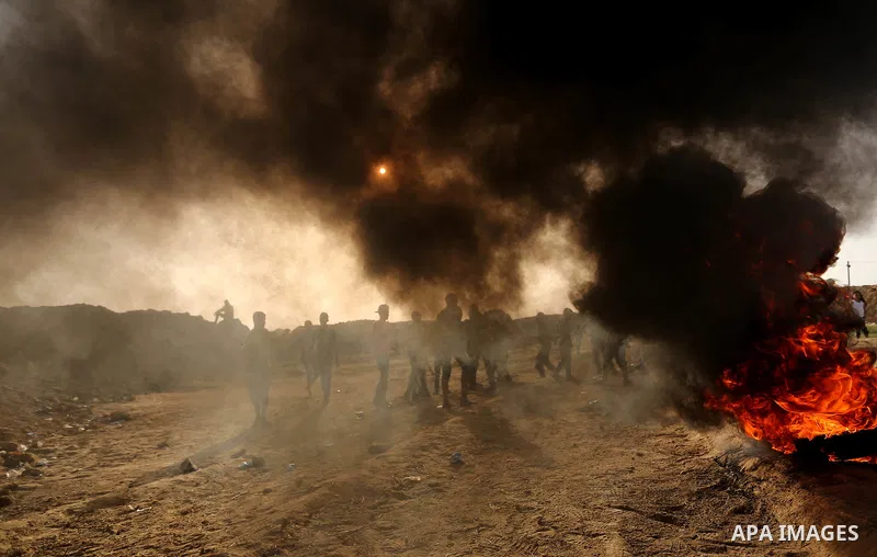 Palestinian protesters hurl stones towards Israeli security forces during clashes on the border between Israel and the Gaza Strip, in al-Bureij in the center of Gaza Strip on April 18, 2018. Photo by Ashraf Amra