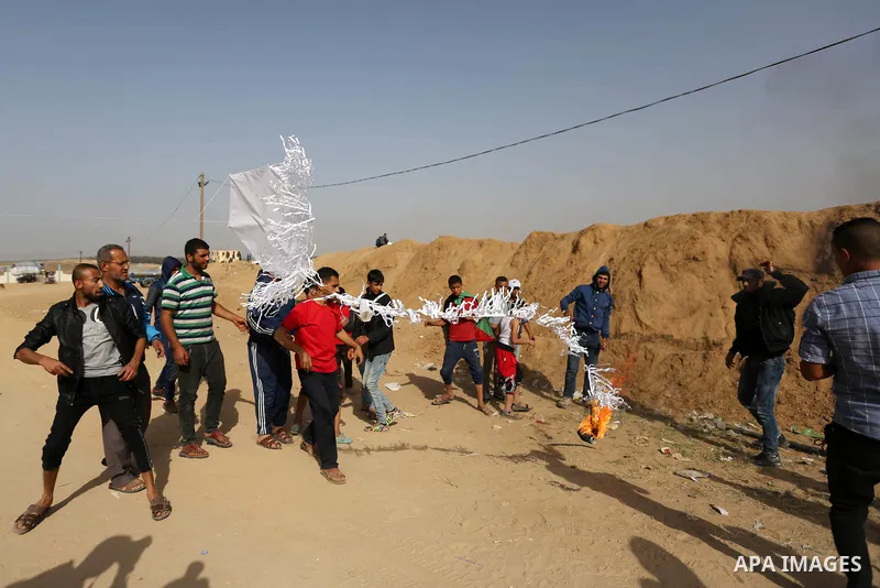 Palestinian youths attempt to fly a kite laden with a molotov cocktail over the border with Israel before cutting the string across the fence, in al-Bureij in the center of Gaza Strip on April 18, 2018. Photo by Ashraf A...