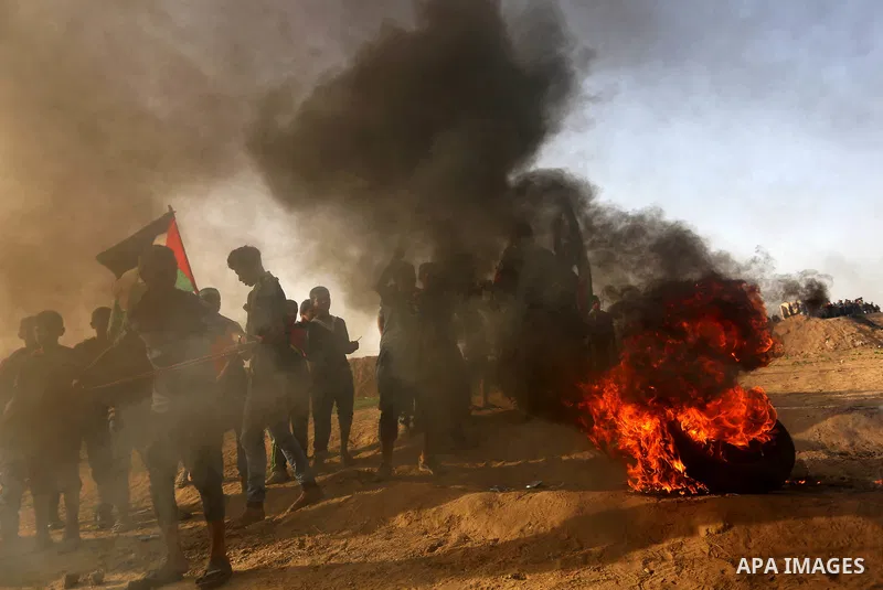 Palestinian protesters hurl stones towards Israeli security forces during clashes on the border between Israel and the Gaza Strip, in al-Bureij in the center of Gaza Strip on April 18, 2018. Photo by Ashraf Amra