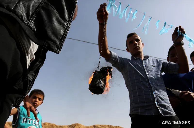 Palestinian youths attempt to tie a molotov cocktail with a string to a kite before trying to fly it over the border fence with Israel, in al-Bureij in the center of Gaza Strip on April 18, 2018. Photo by Ashraf Amra