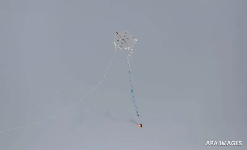 A picture taken on April 18, 2018 shows a kite laden with a molotov cocktail being flown by Palestinian youths over the border with Israel before cutting the string across the fence, in al-Bureij in the center of Gaza St...