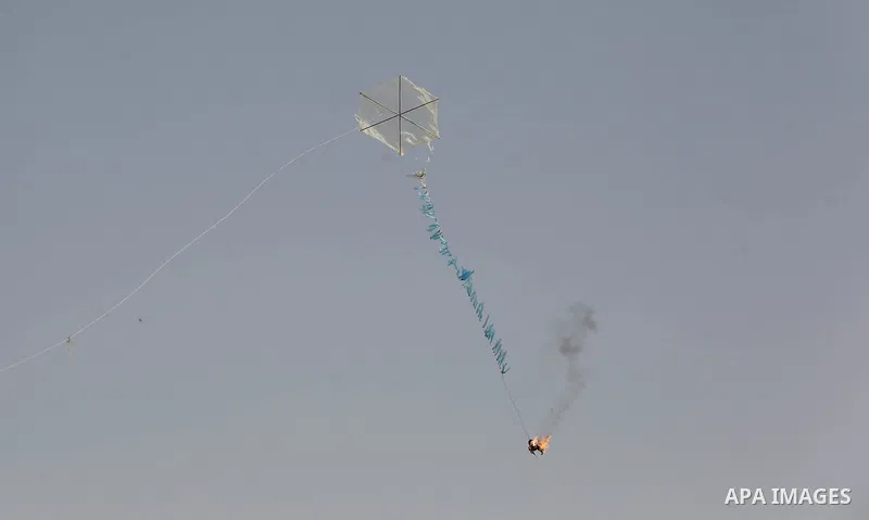 A picture taken on April 18, 2018 shows a kite laden with a molotov cocktail being flown by Palestinian youths over the border with Israel before cutting the string across the fence, in al-Bureij in the center of Gaza St...