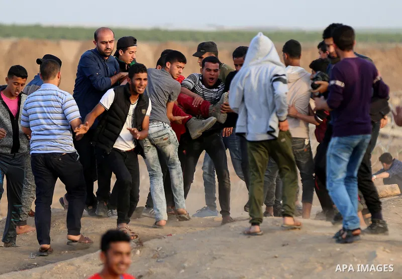 Palestinians evacuate an injured protester during clashes with Israeli security forces near the border with Israel, east of Gaza City, April 18, 2018. Photo by Yasser Qudih