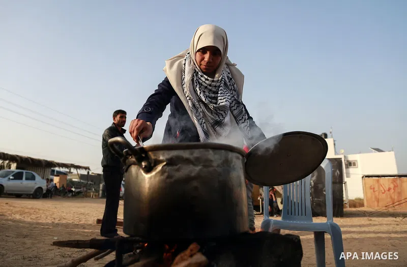 Palestinian women prepare Couscous during a tent city protest along Israel border with Gaza, demanding to return to their homeland, east of Gaza City, April 18, 2018. Photo by Mohammed Dahman