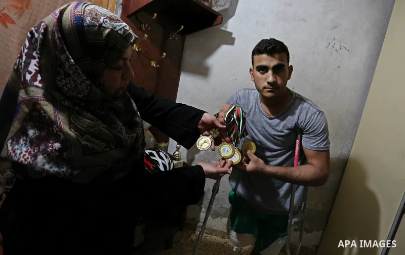 Palestinian cyclist Alaa Al-Daly, 21, who lost his leg by a bullet fired by Israeli troops along the Gaza border during a protest, holds trophies he has won in competitions, at his home in Rafah in the southern Gaza Stri...