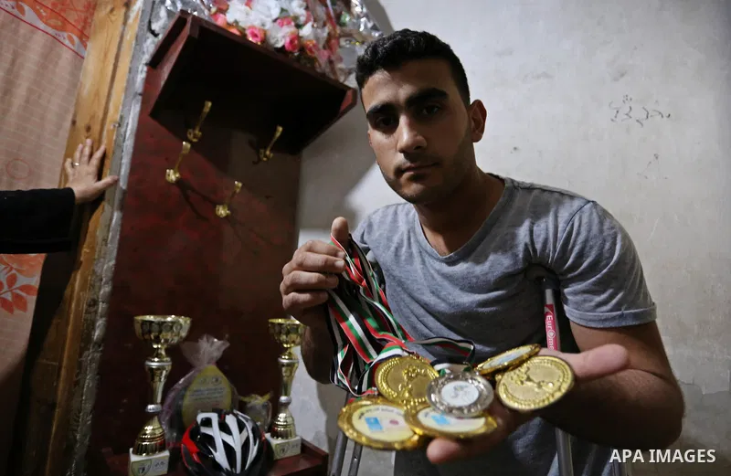 Palestinian cyclist Alaa Al-Daly, 21, who lost his leg by a bullet fired by Israeli troops along the Gaza border during a protest, holds trophies he has won in competitions, at his home in Rafah in the southern Gaza Stri...