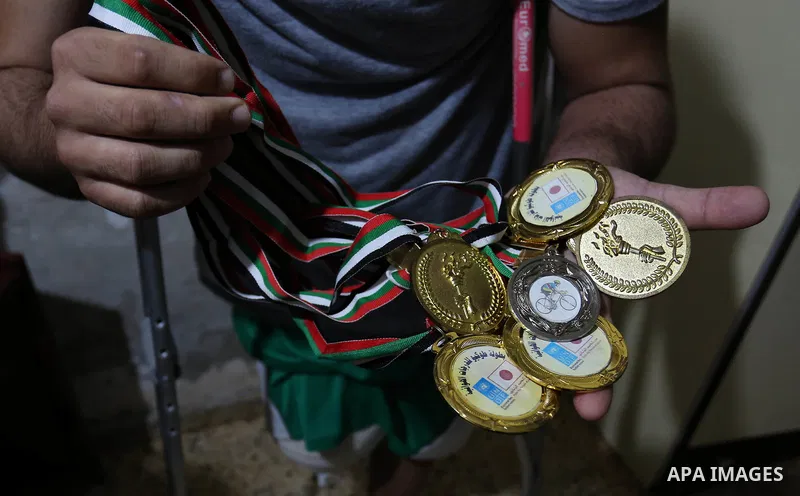 Palestinian cyclist Alaa Al-Daly, 21, who lost his leg by a bullet fired by Israeli troops along the Gaza border during a protest, holds trophies he has won in competitions, at his home in Rafah in the southern Gaza Stri...