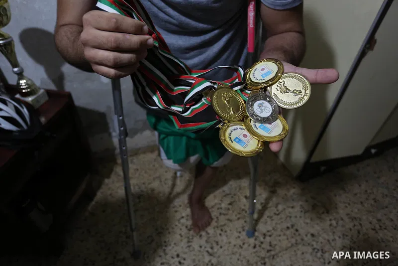 Palestinian cyclist Alaa Al-Daly, 21, who lost his leg by a bullet fired by Israeli troops along the Gaza border during a protest, holds trophies he has won in competitions, at his home in Rafah in the southern Gaza Stri...