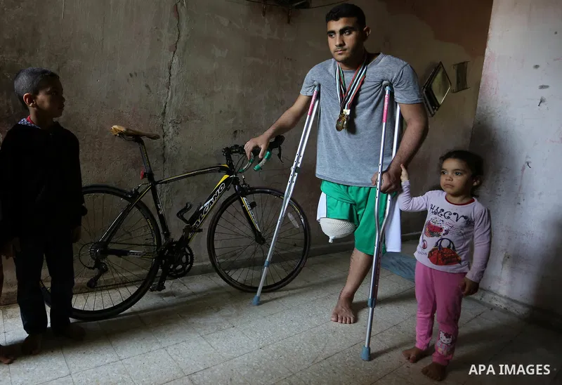 Palestinian cyclist Alaa Al-Daly, 21, who lost his leg by a bullet fired by Israeli troops along the Gaza border during a protest, stands next to his bicycle, at his home in Rafah in the southern Gaza Strip on April 19,...