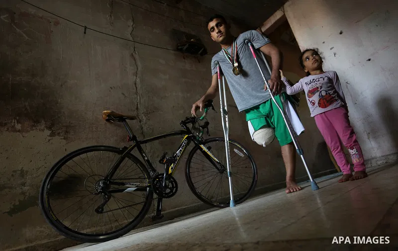 Palestinian cyclist Alaa Al-Daly, 21, who lost his leg by a bullet fired by Israeli troops along the Gaza border during a protest, stands next to his bicycle, at his home in Rafah in the southern Gaza Strip on April 19,...