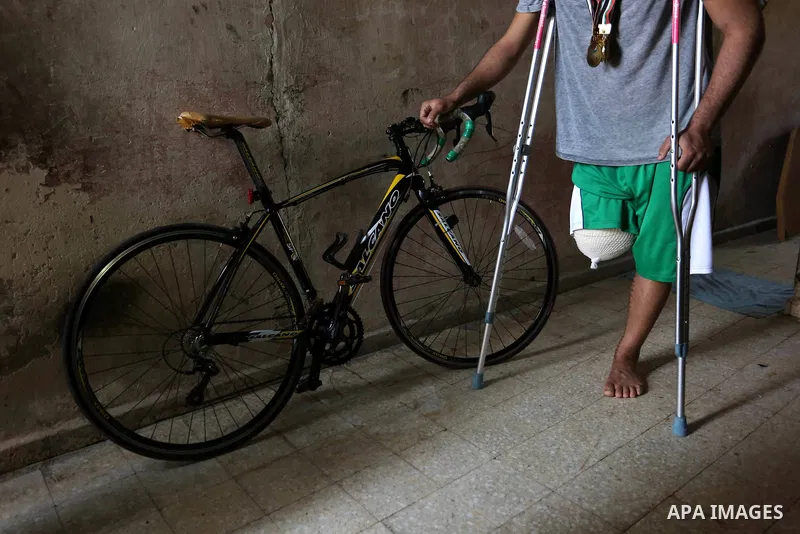 Palestinian cyclist Alaa Al-Daly, 21, who lost his leg by a bullet fired by Israeli troops along the Gaza border during a protest, stands next to his bicycle, at his home in Rafah in the southern Gaza Strip on April 19,...