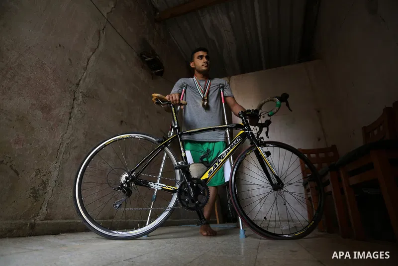 Palestinian cyclist Alaa Al-Daly, 21, who lost his leg by a bullet fired by Israeli troops along the Gaza border during a protest, stands next to his bicycle, at his home in Rafah in the southern Gaza Strip on April 19,...