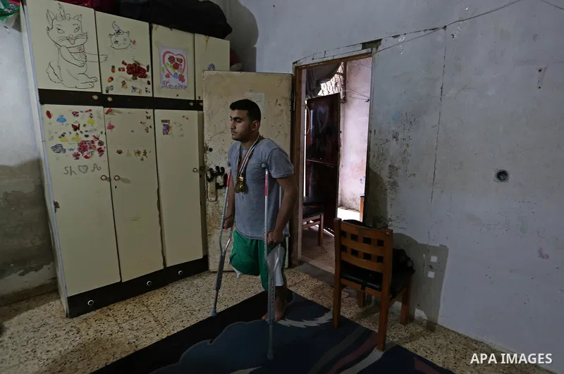 Palestinian cyclist Alaa Al-Daly, 21, who lost his leg by a bullet fired by Israeli troops along the Gaza border during a protest, walks using crutches at his home in Rafah in the southern Gaza Strip on April 19, 2018. D...