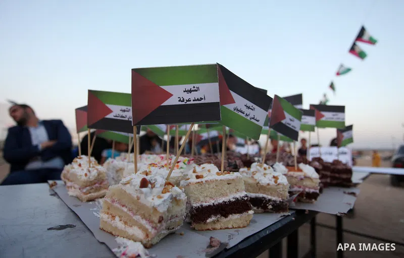 Palestinians cut cake during a protest at the Israel-Gaza border where Palestinians demand the right to return to their homeland, east of Gaza City April 19, 2018. Photo by Mahmoud Ajour